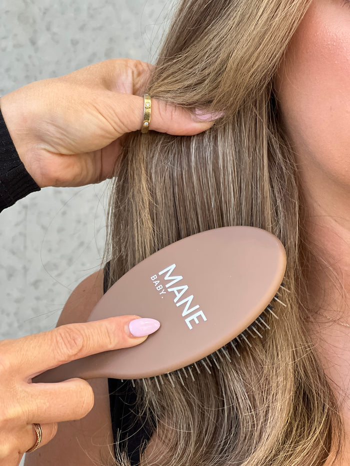 The Mane Baby Original brush being used to smooth long blonde hair