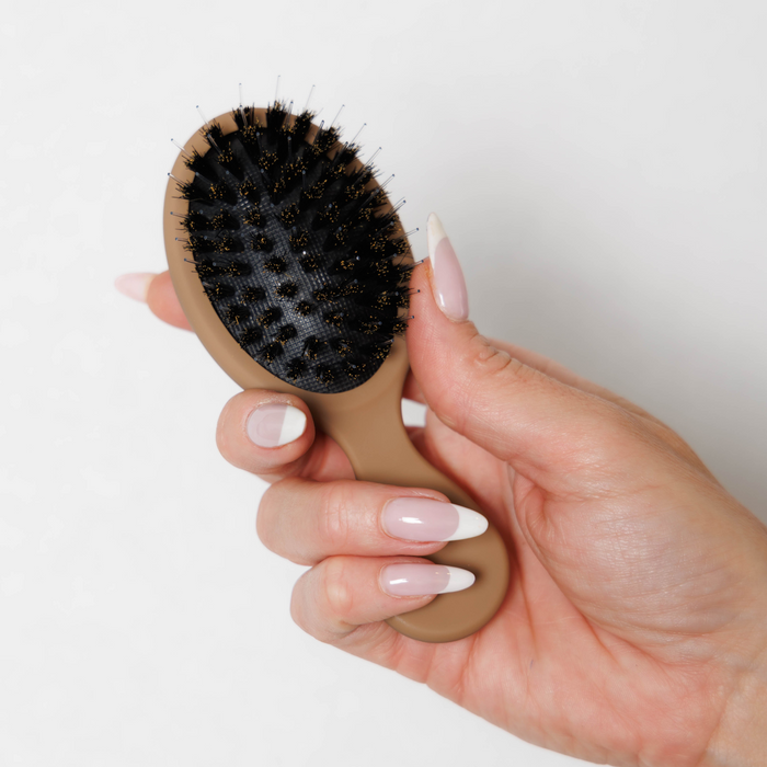 Bristle side of the Mane Baby Mini Boar Bristle Brush held in hand, showing its compact size