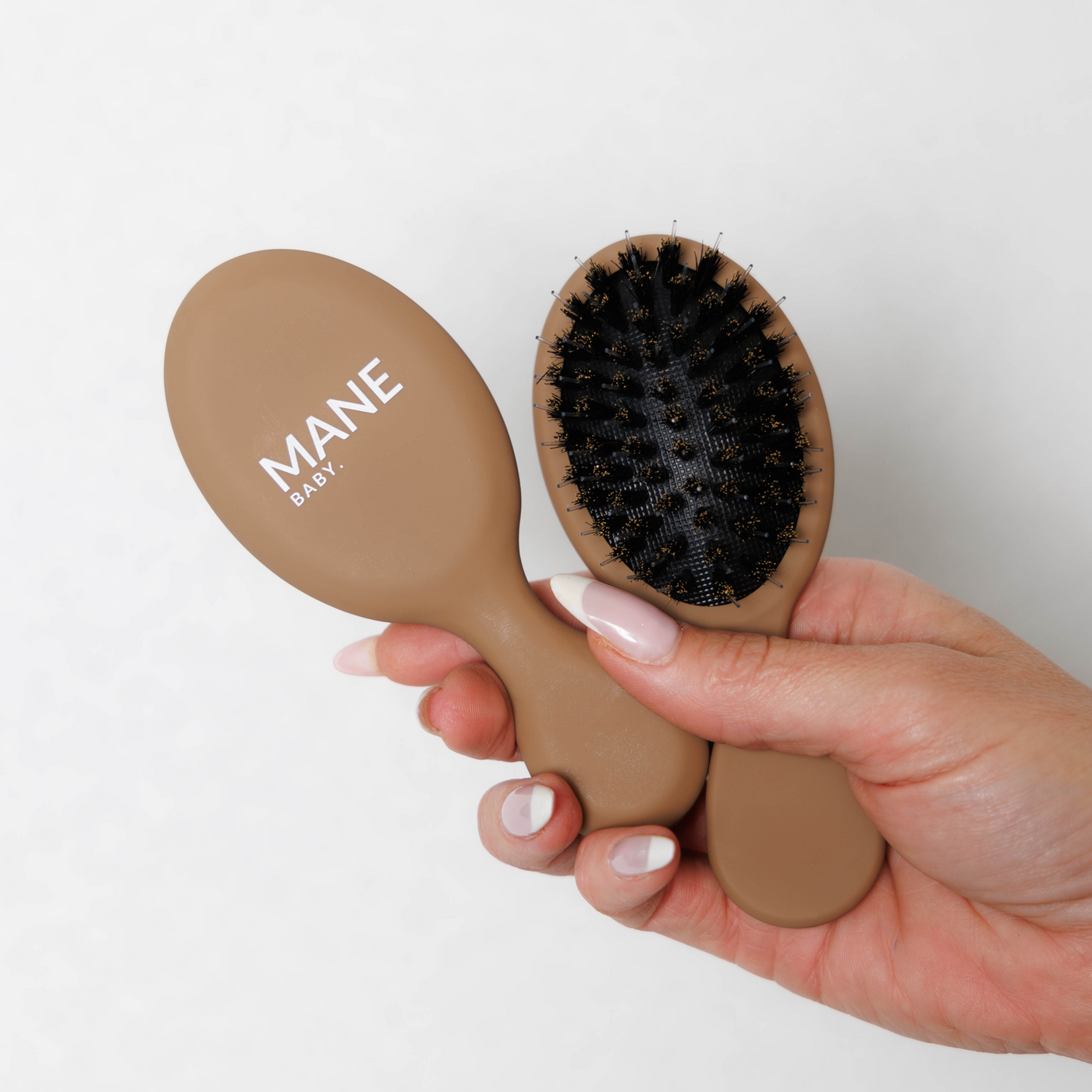 Mane Baby Mini Boar Bristle Brush held in hand, showing both the branded back and the bristle side