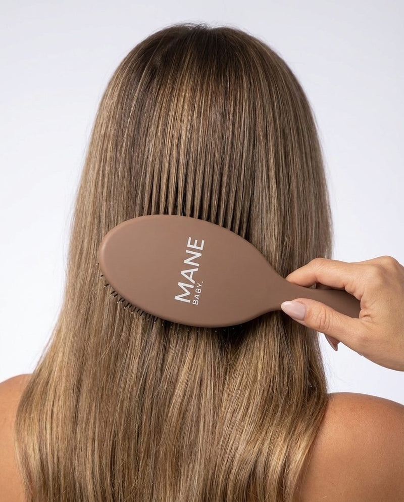 The Mane Baby Original brush mid-stroke through long bronde hair